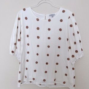 White polagram top with tan poofs